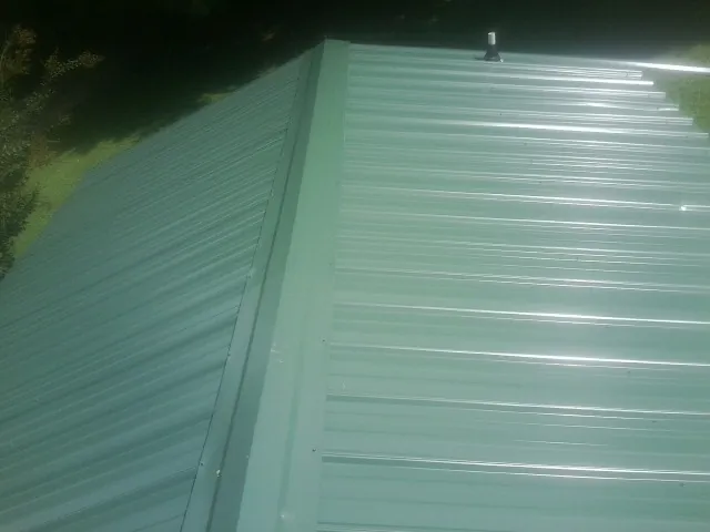 New green metal panels meeting at the ridge of a roof — Flat Roof Repair work by our crew in Norwalk